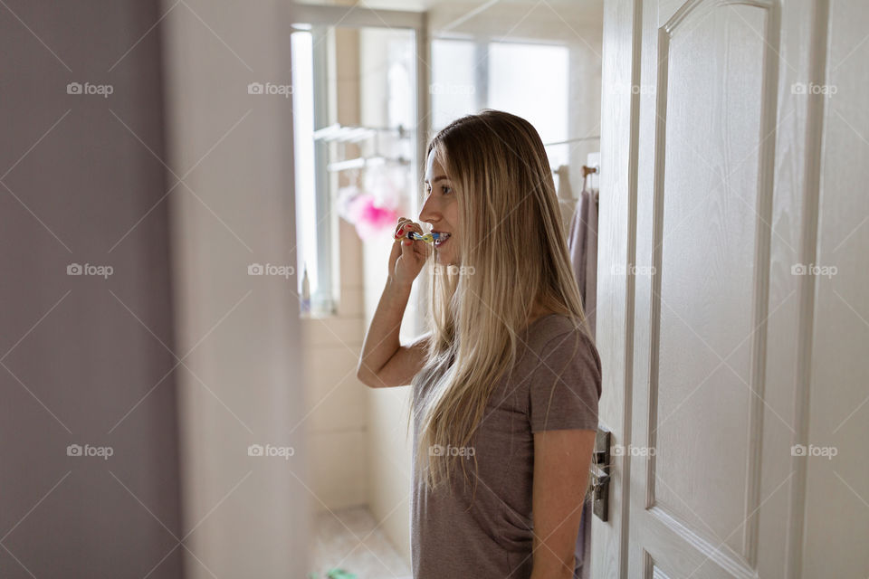 Woman cleaning teeth in bathroom 