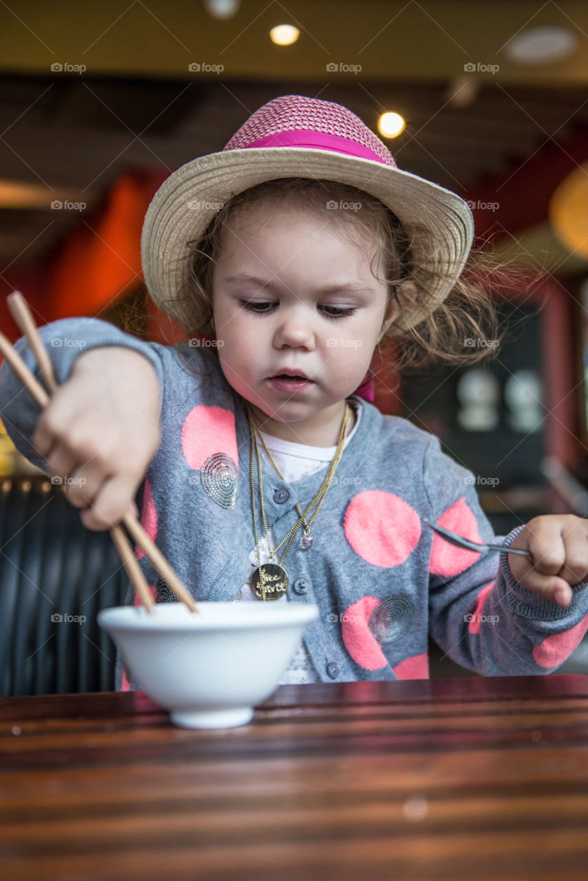 Girl eating food with chopstick in bowl