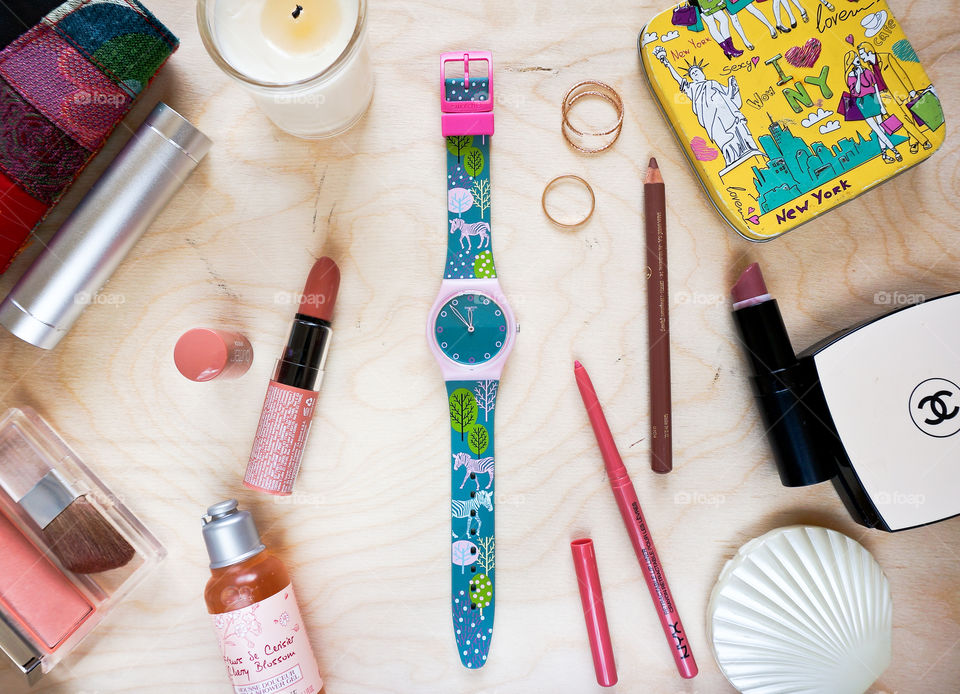 Green zebra Swatch watch flatlay with accessories and cosmetics