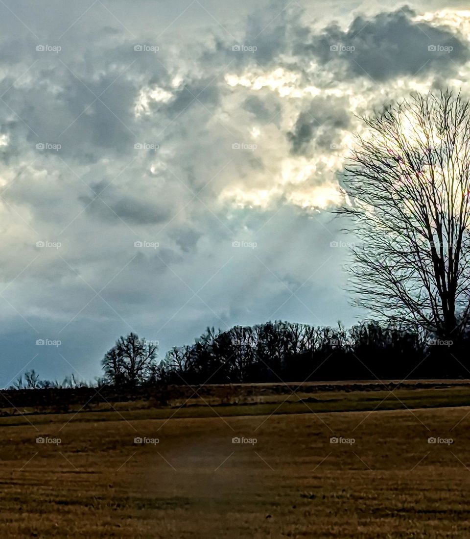 Sunbeams touching the field during a break in the clouds on a rainy winter day.