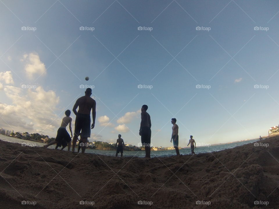 Shirtless men playing beach volleyball