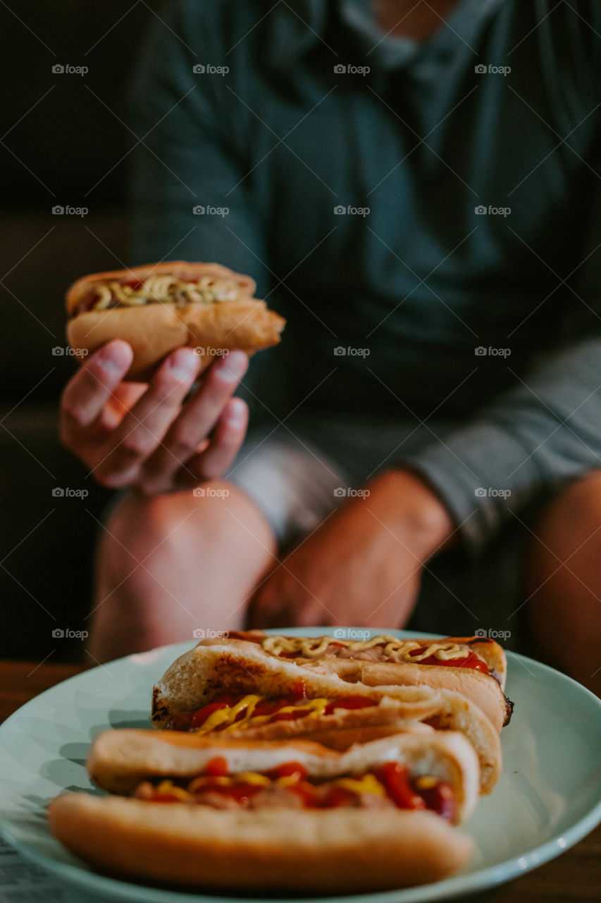 Man eating a hot dog while watching tv 