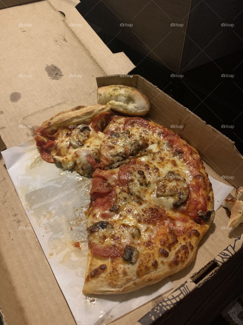 Pizza half eaten in box 