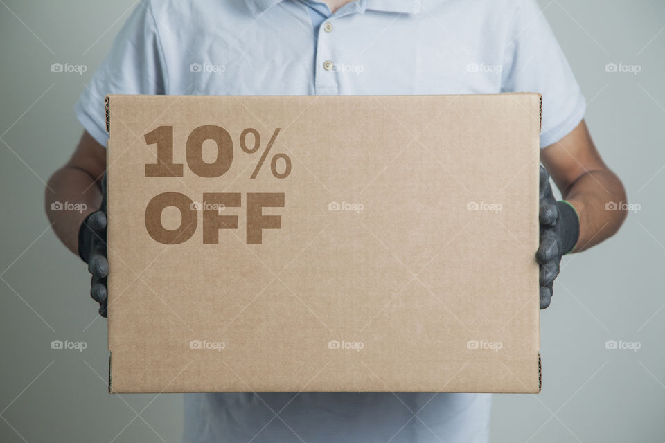 Cardboard box with 10% off order written on the box placed on the floor in an empty room with a neutral background. delivery concept. economy concept. business concept. shopping concept. copy space.