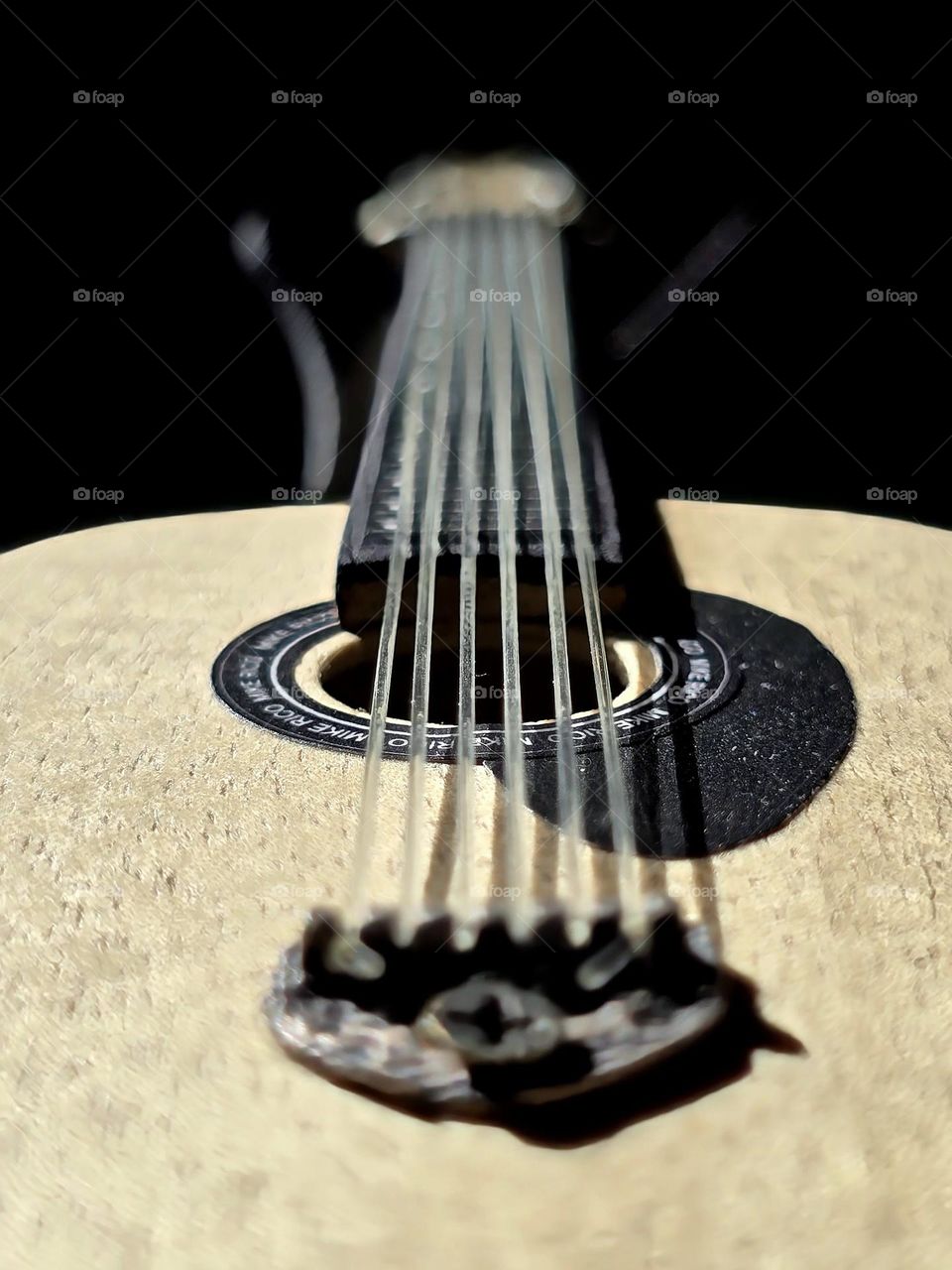 Small collection guitar placed on a table with dark background while receiving sunlight on it.