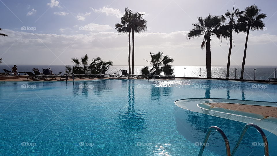 Beautiful swimming pool area with palm trees and view of the ocean in fair weather -  fint poolområde med palmer och utsikt över havet i fint väder 