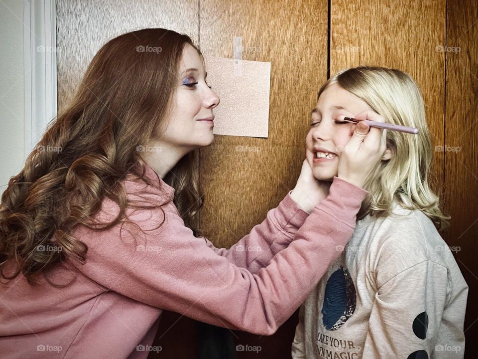 A mother doing her daughter’s makeup for a fun special day