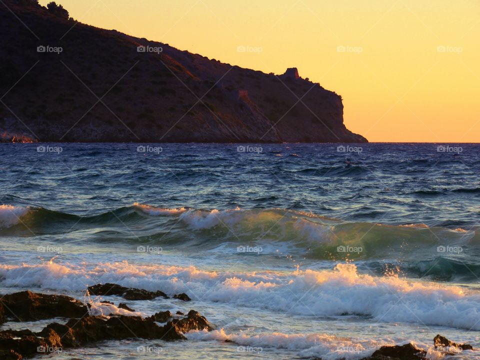 Waves at rocky coastline during sunset