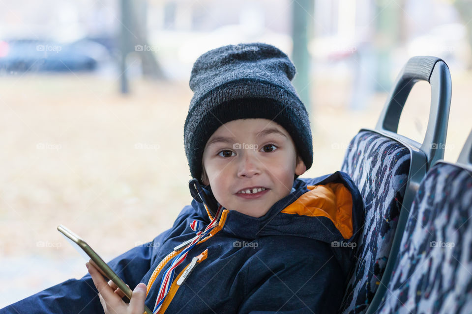 Boy with phone smiling. Preschool boy smiling, with smart phone in bus
