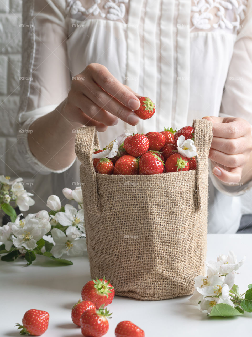 Putting strawberry in a jute bag full of strawberries 