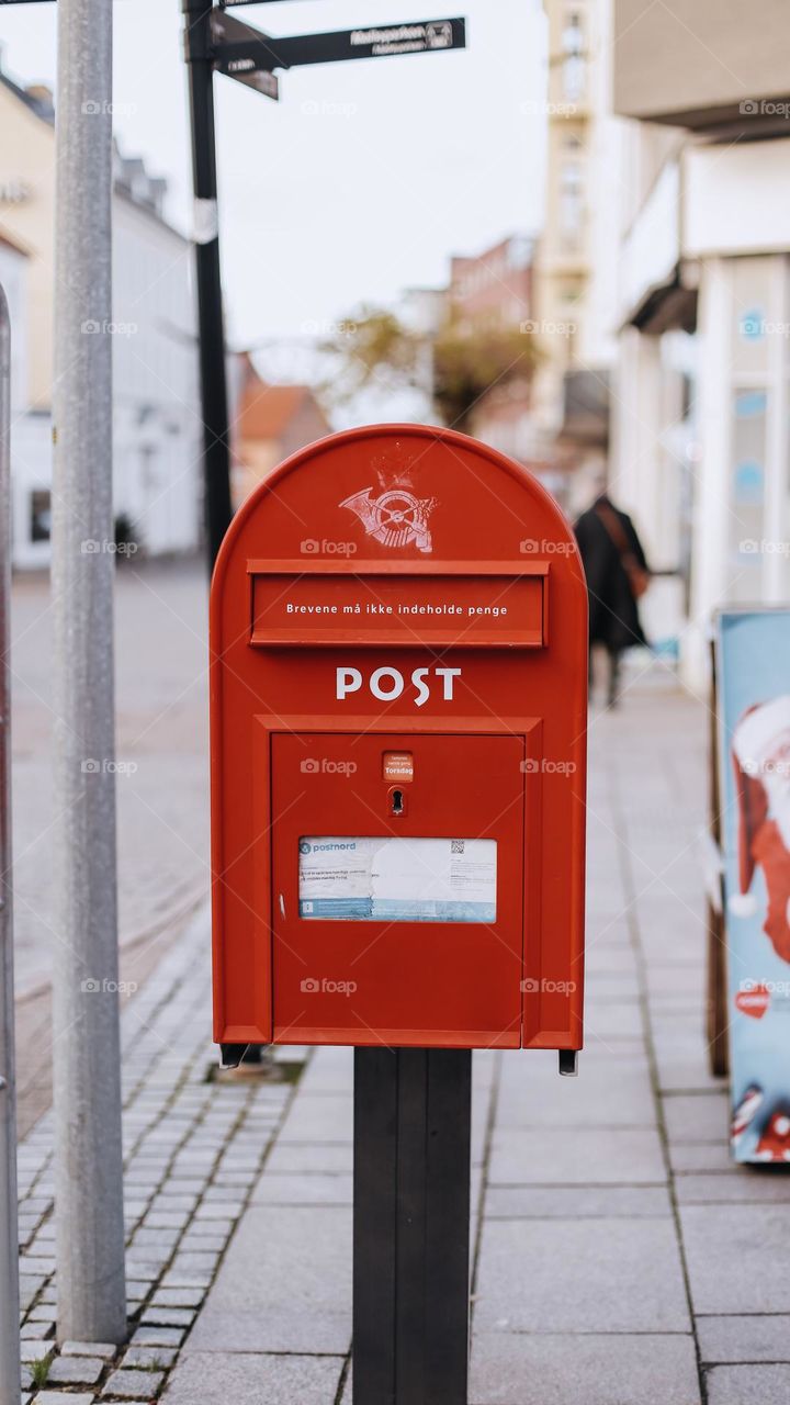 a beautiful, red mailbox contrasts with the gray local street