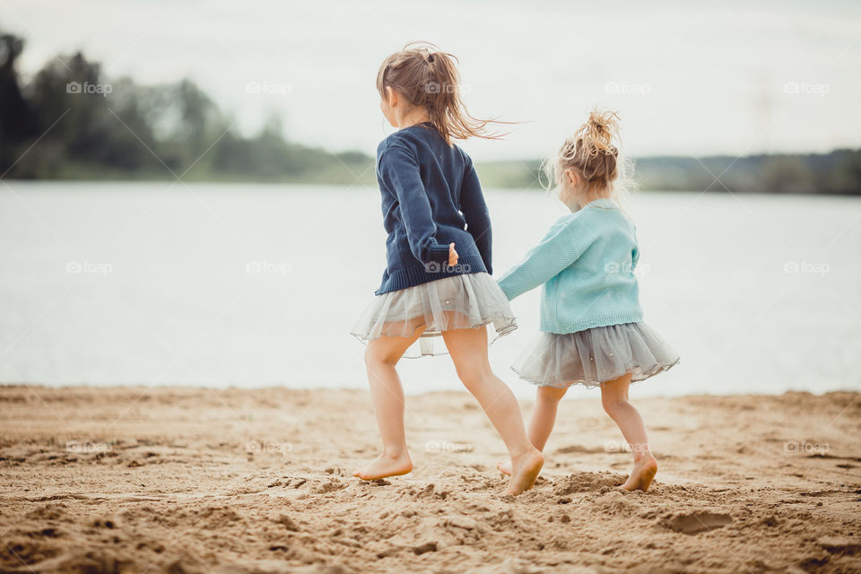 Little sisters on lake coast at sunny evening. portrait, picnic, lake, summer, coast, child, girl, childhood, water , outdoor, sisters, family, friends, friendship 