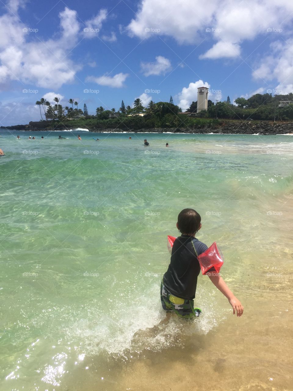 Boy on the beach wearing arm bands/floaties 