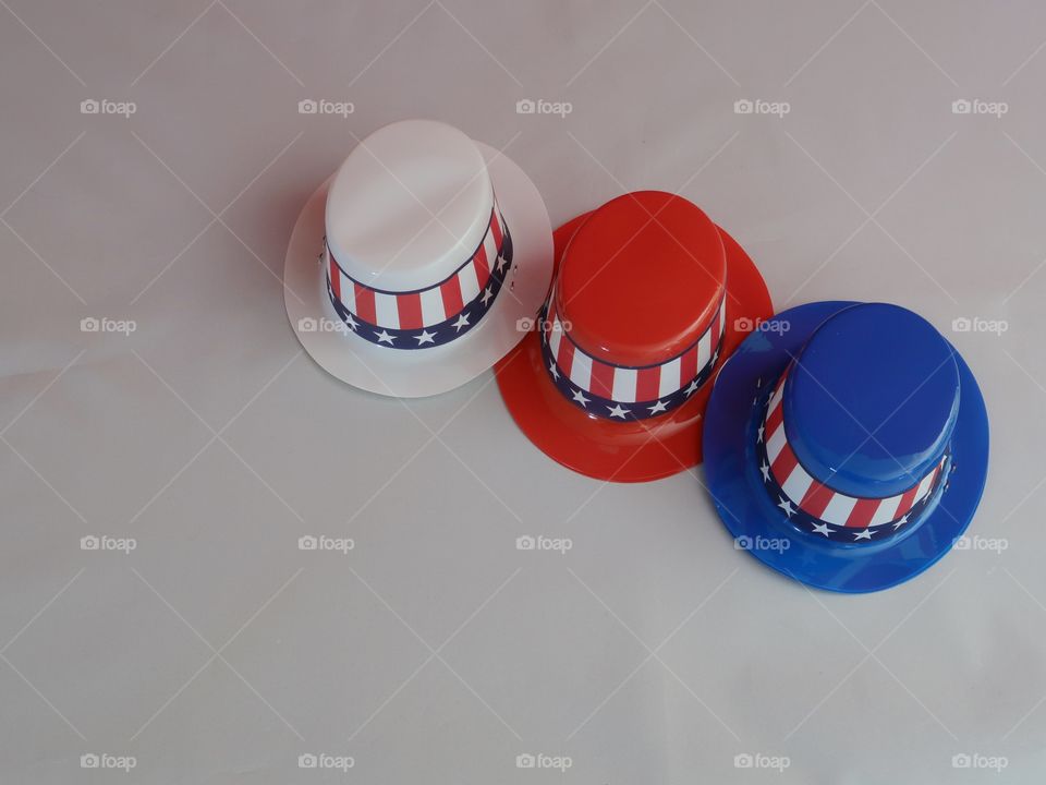 Tiny party hats in red, white, and blue with the Stars and Stripes for hat bands on a table with confetti. 