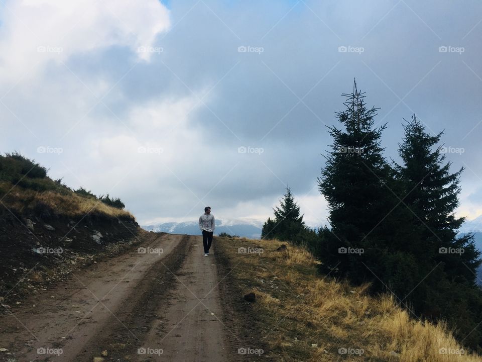 Single man walking alone on a forest road 