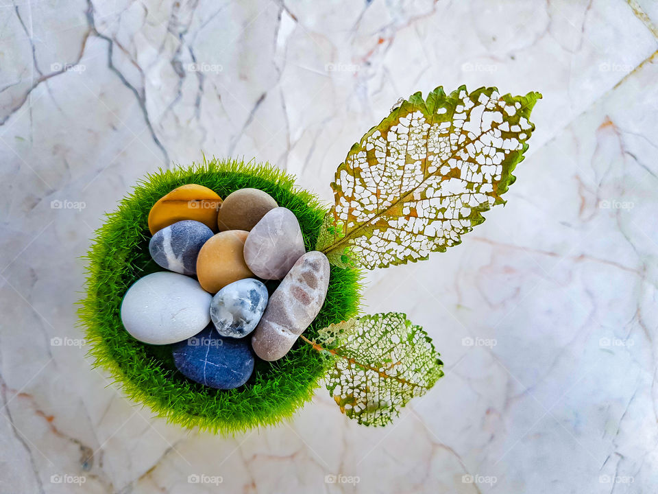 colourful pebbles on a grass vase decorated with a fallen leaf of a tree, the pattern on the leaf is all natural