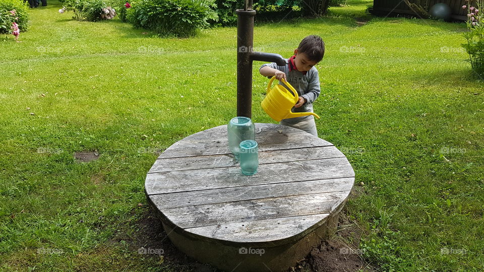 cute toddler working in farm with water well