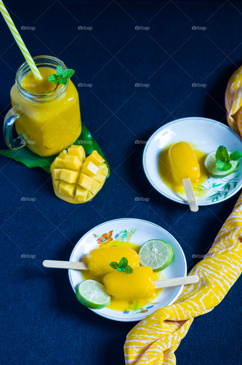 Mouthwatering mango popsicles and mango juice ready for hot summer. Mango refreshment.