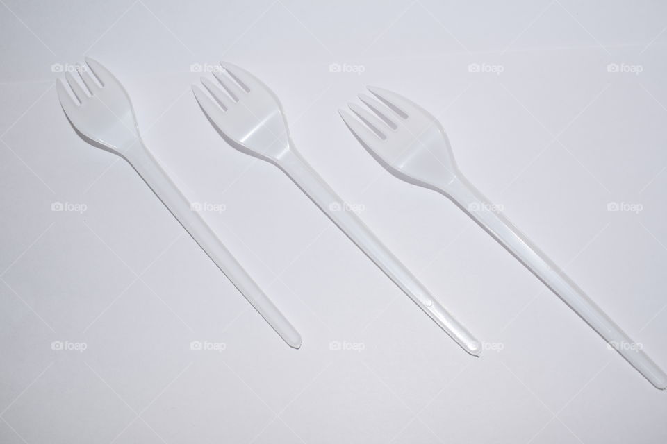three disposable forks on a white background lie