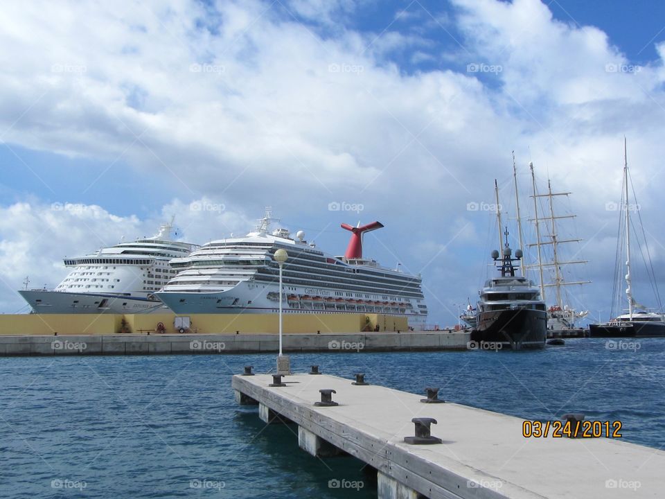 Two cruise ships, fishing boat, wharf, carribean water & sky.