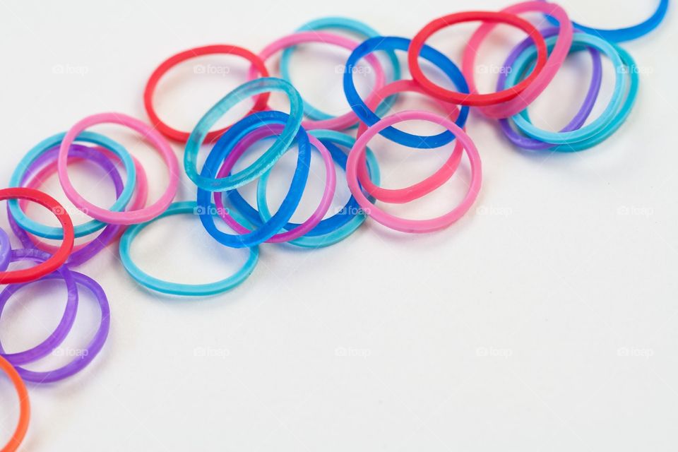 Brightly colored rubber bands against a white background. Child's craft supplies.