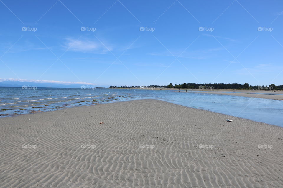 Wide sandy beach and low tide , water starting coming making rivers on the beach . Parksville, British Columbia 