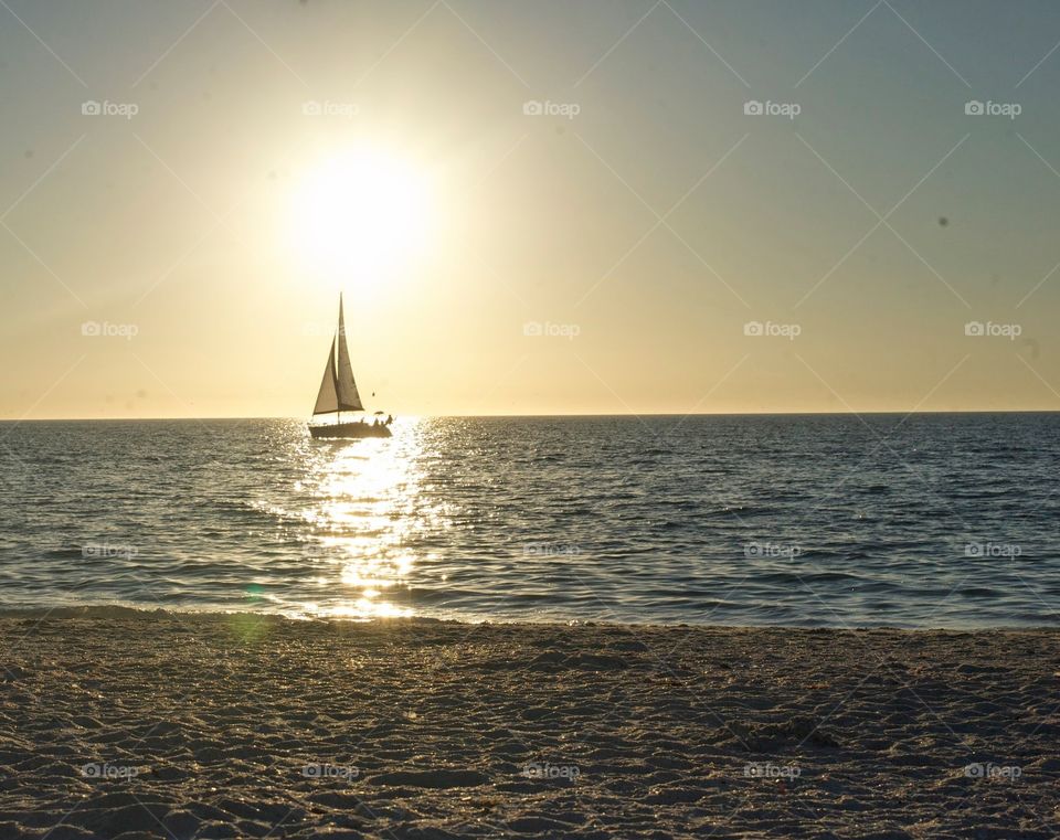 sailing the sunset. sitting in beach waiting for sunset. 