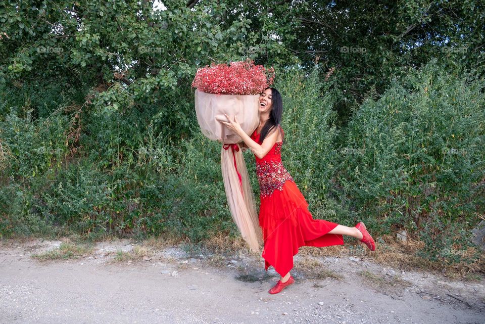 Woman Dances with a Large Bouquet of Red Flowers