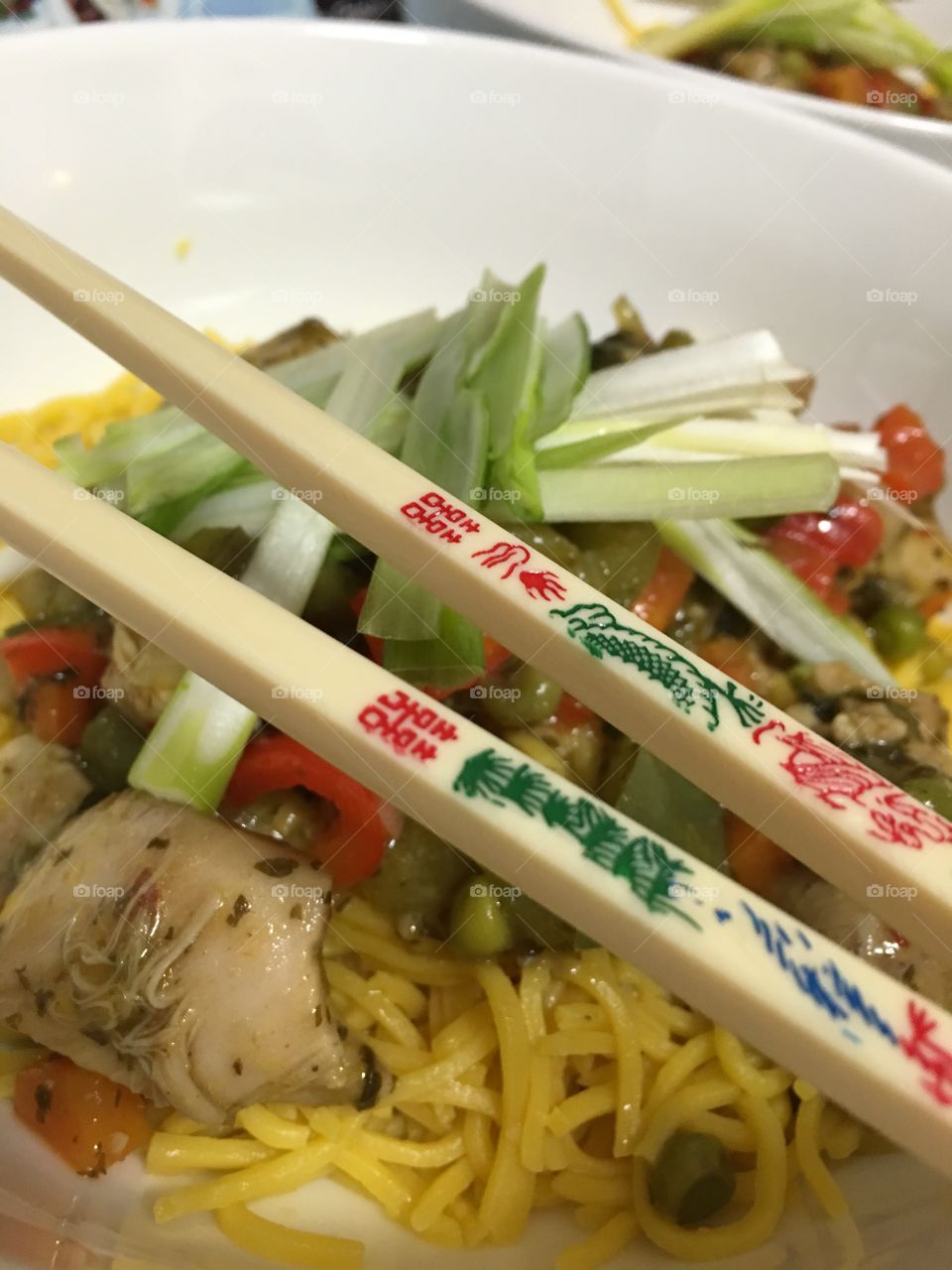 Closeup chopsticks atop bowl of Asian food