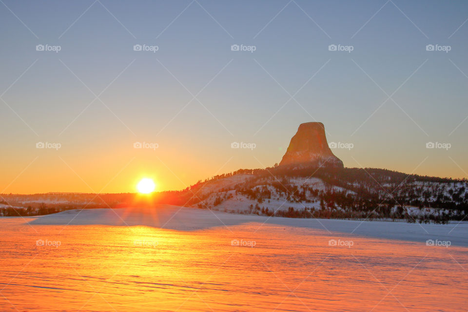 Devil's Tower in the snow at sunset. 