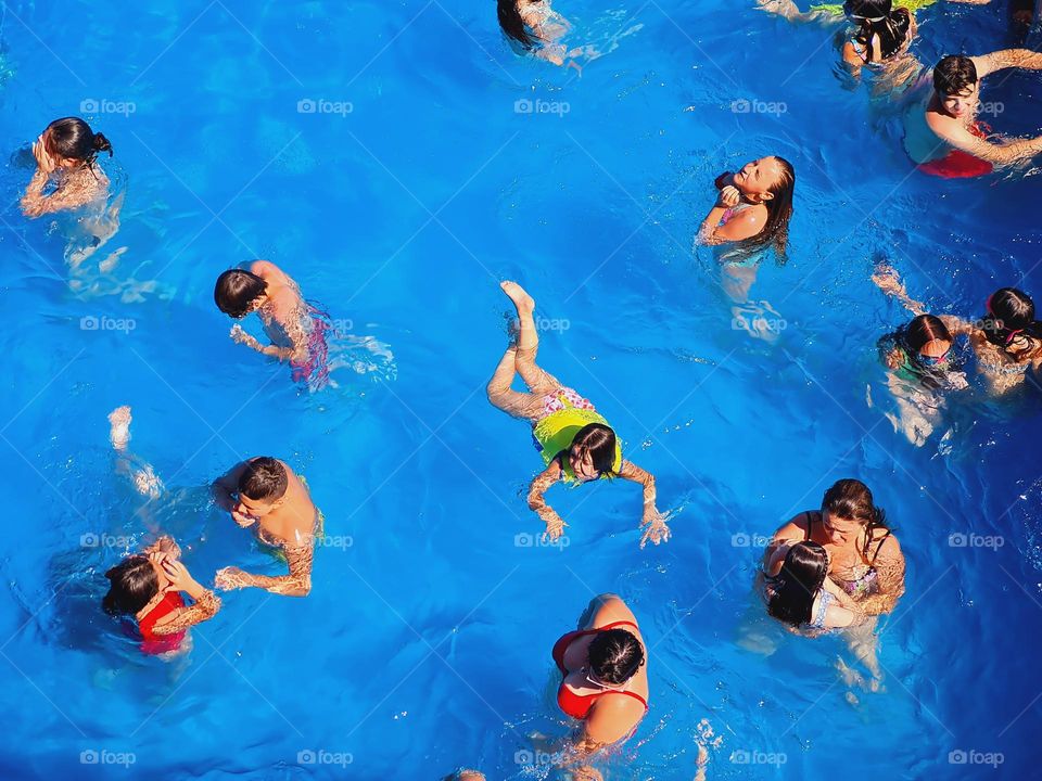 overhead photo of children having fun in the swimming pool on a hot summer afternoon