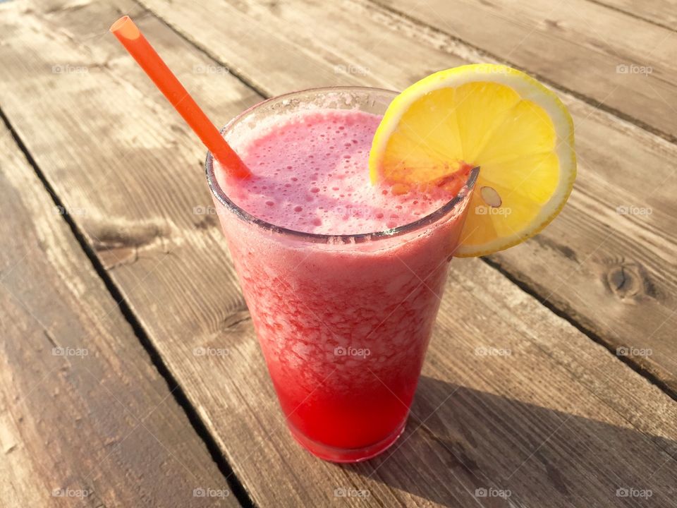 Glass of strawberry lemonade on wooden dock