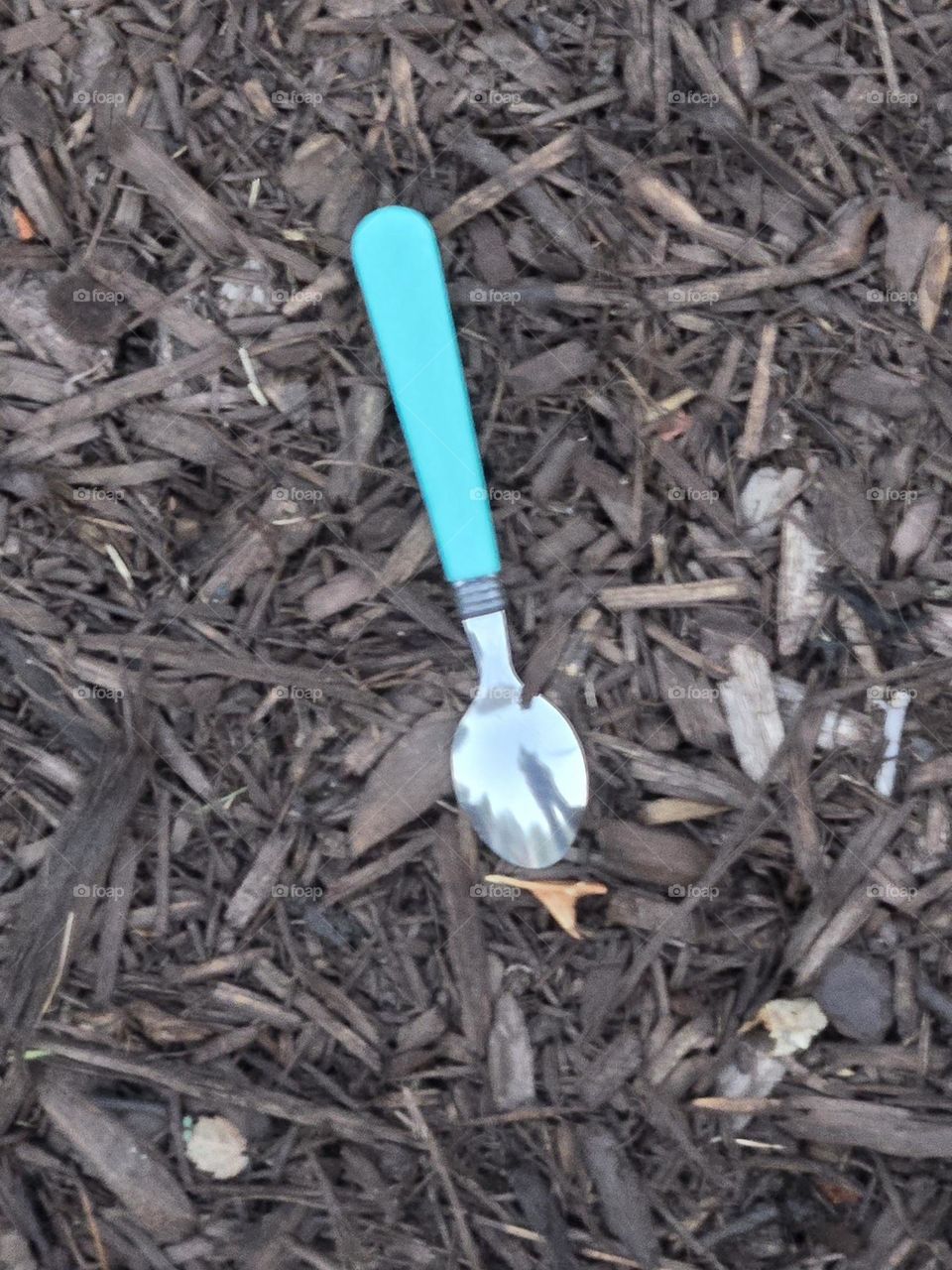 A spoon in the ground with a reflection. Why is it there? It's a mystery.