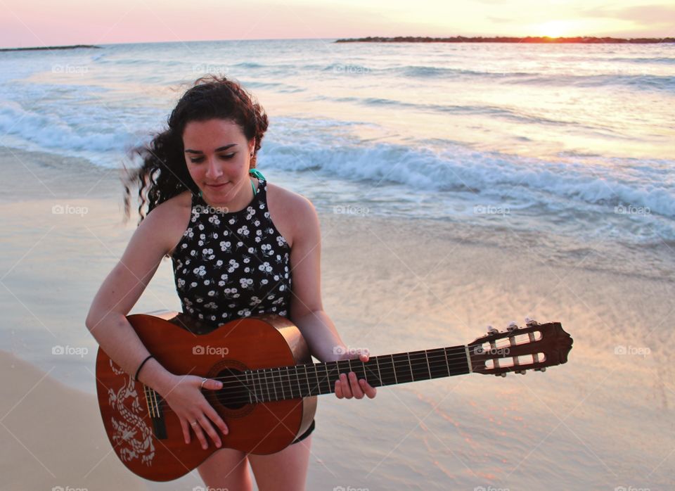 Woman holding guitar at beach
