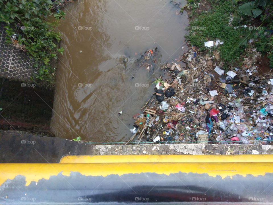 a lot of garbage on the riverbank taken from the bridge