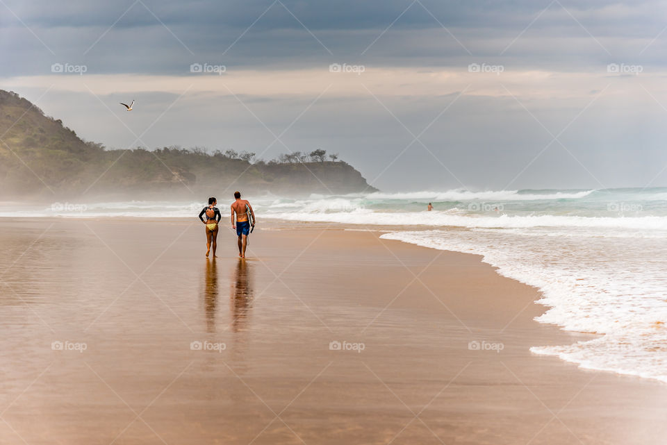 Surfers strolling along g the beach