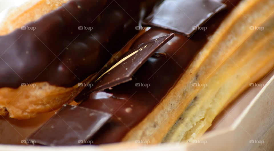 Rich dark chocolat indulgence elegant éclairs with chocolate squares in puff pastry epicure closeup photography fully frame 