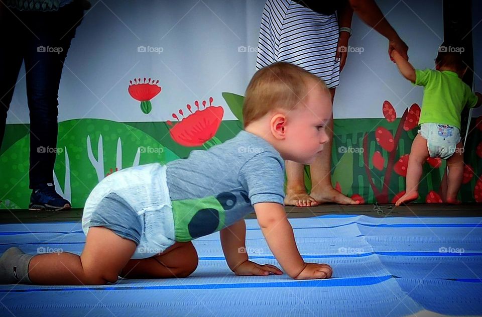 Small children.  Competition who is faster.  A little boy in a diaper crawls intently towards the finish line