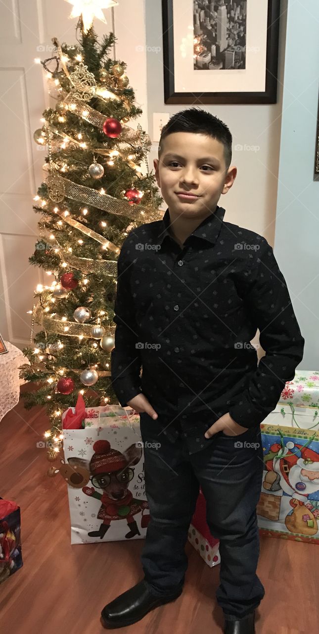 My son posing in front of the Christmas tree