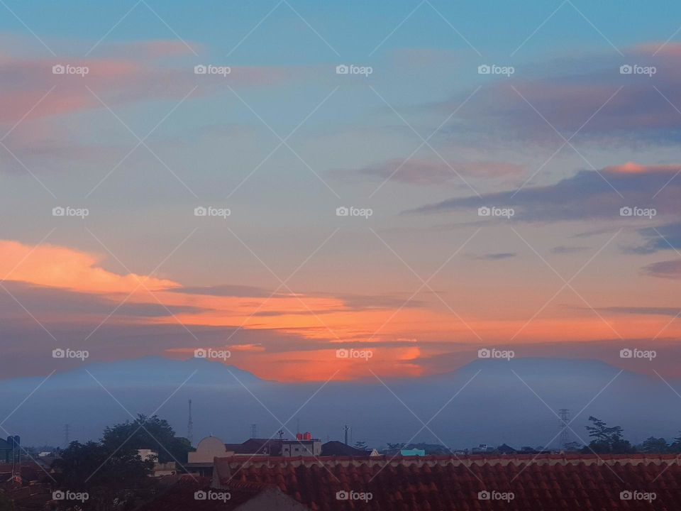 The view in the morning, the sky is cloudy and quite thich fog, the sky is a little blue, the clouds look red, the air feels cold