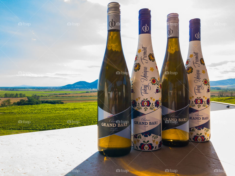 Four bottles of wine placed on quartz ledge with nice background view on vine fields and hills. Brand: Grand Bari, Location: Southern Slovakia, 076 32 Bara, Chateau Grand Bari 🇸🇰