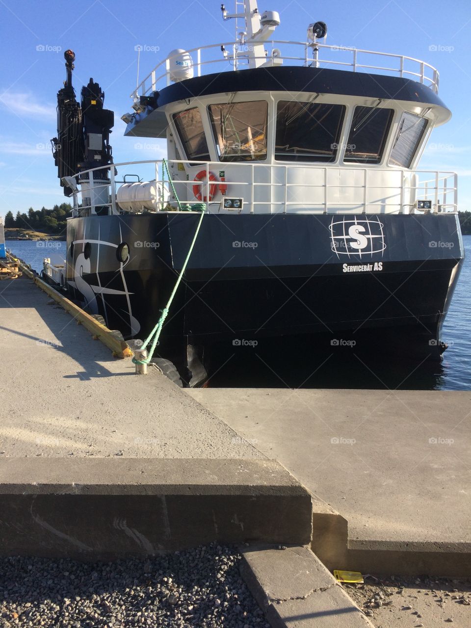 A ship docked by the port where I live a sunny evening during the summer. The ship is mainly used for crane operations at fish farms. It repairs and do maintenance
