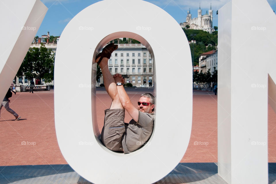 Man seated inside the O in the only Lyon France sculpture