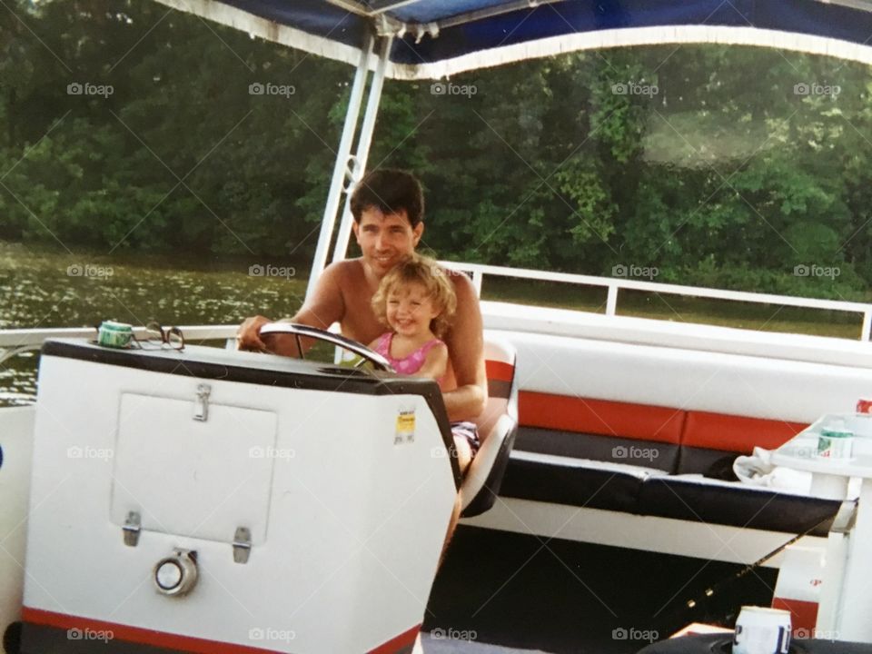 Little girl driving boat with her father