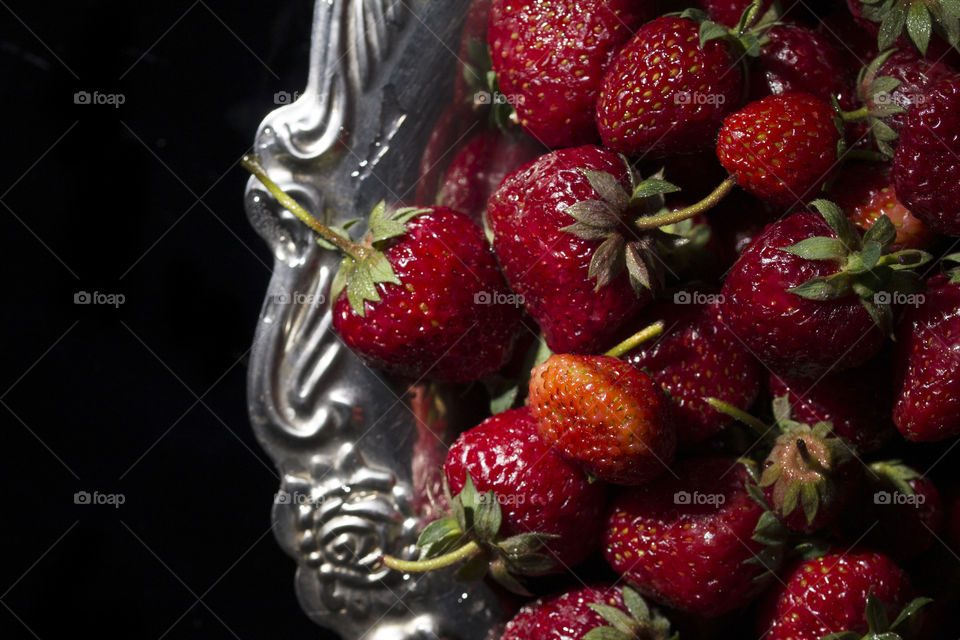 top view of red ripe strawberry on silver plate .