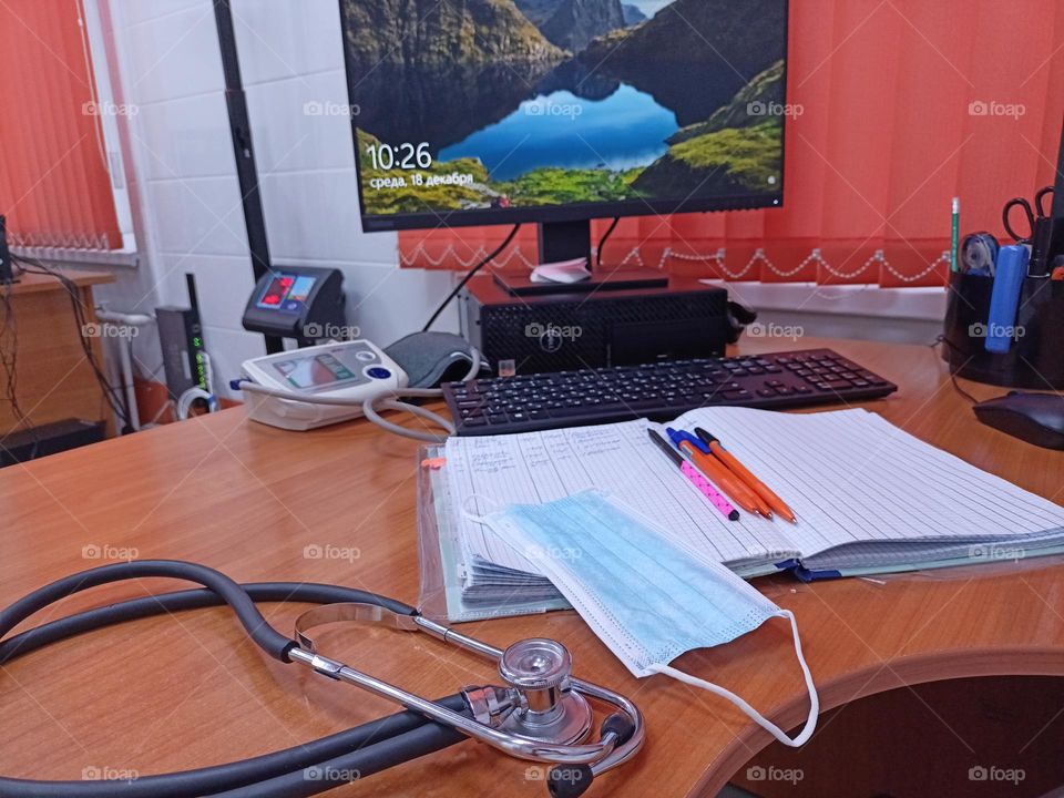 Doctor's desk, computer desk,monitor, blinds, orange,magazines,pens,phonendoscope,medical mask,doctor's office, reception room