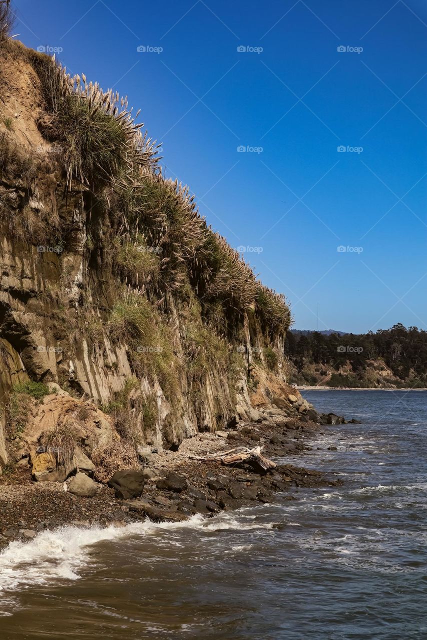 View of the cliffs in Capitola California on a crystal clear day with a clear blue sky as the cold Pacific Ocean waters cool the air