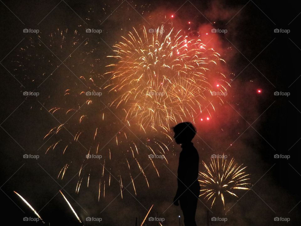silhouette of child staring at summer fireworks