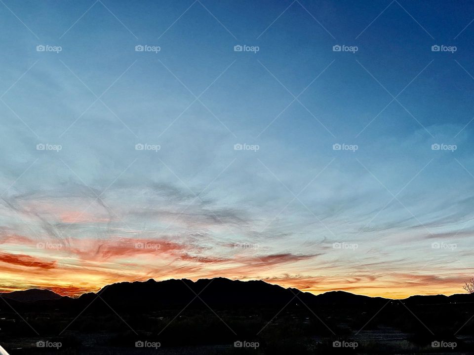 A photo of a cloudy sunset with mountains. 