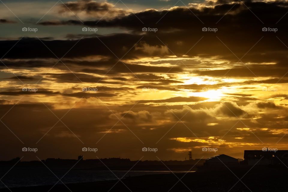 A cloudy orange sunset by the coast